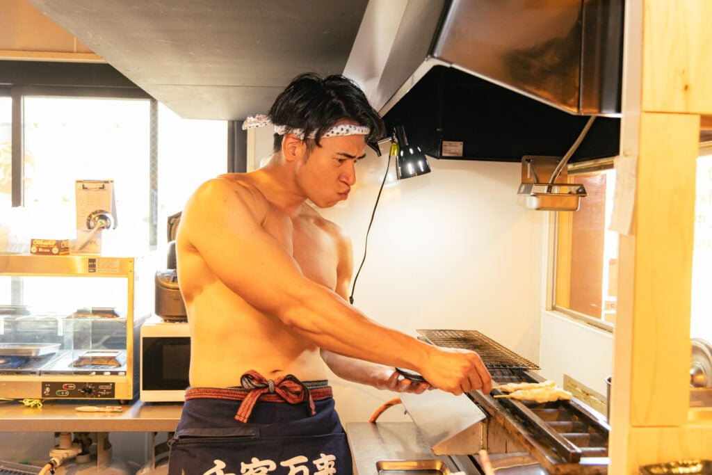Muscly japanese man making yakitori