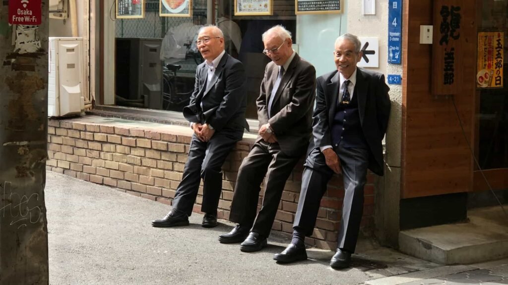 Three elderly workers in Japan sitting and smiling