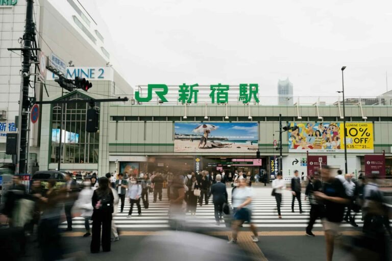 Crowds pass outside of Shinjuku Train Station.