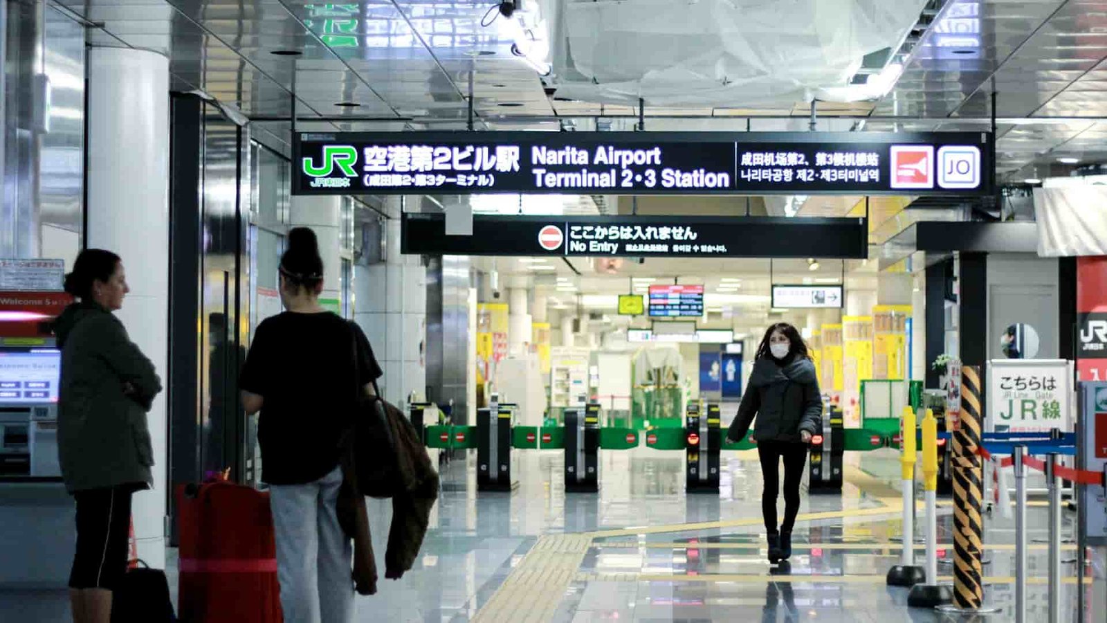 People walking along outside of a ticket gate of a Japanese train station.